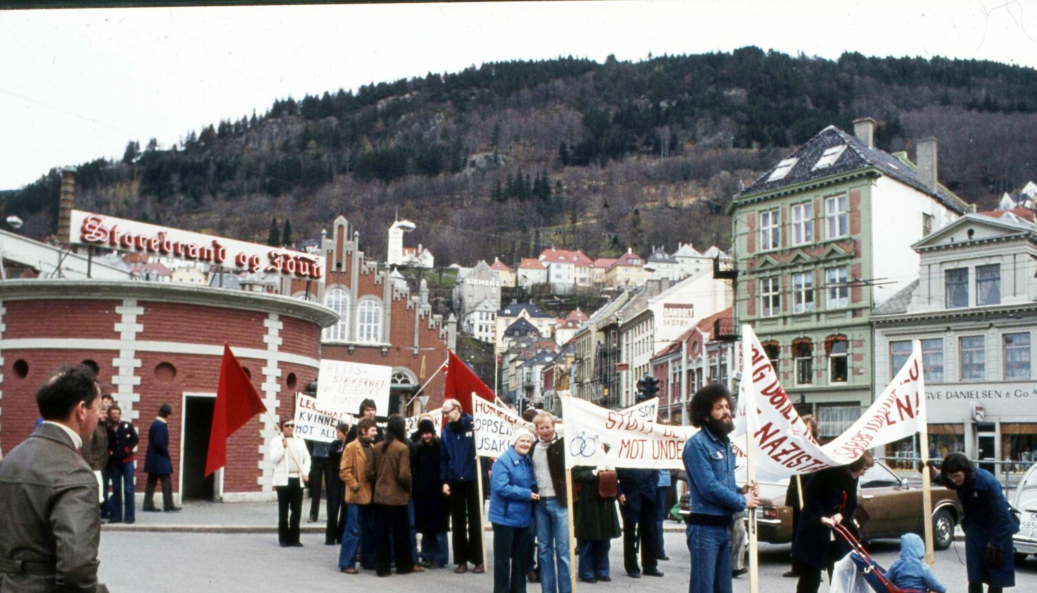 Leif Pareli i grå genser står på Fisketorget i Bergen 1. mai 1976. Han skal bære hovedparolen «Støtt de homofiles kamp mot undertrykking», og for første gang og stå fram som homofil.