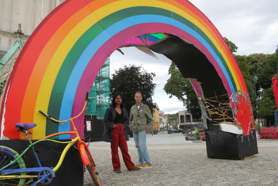 Jaya Helena Seljestad (til venstre) og Irene Bakkevold står bak regnbuen som er plassert på Torvet i Kristiansand. Det er tydelige skader på kunstverket etter flere runder med hærverk.