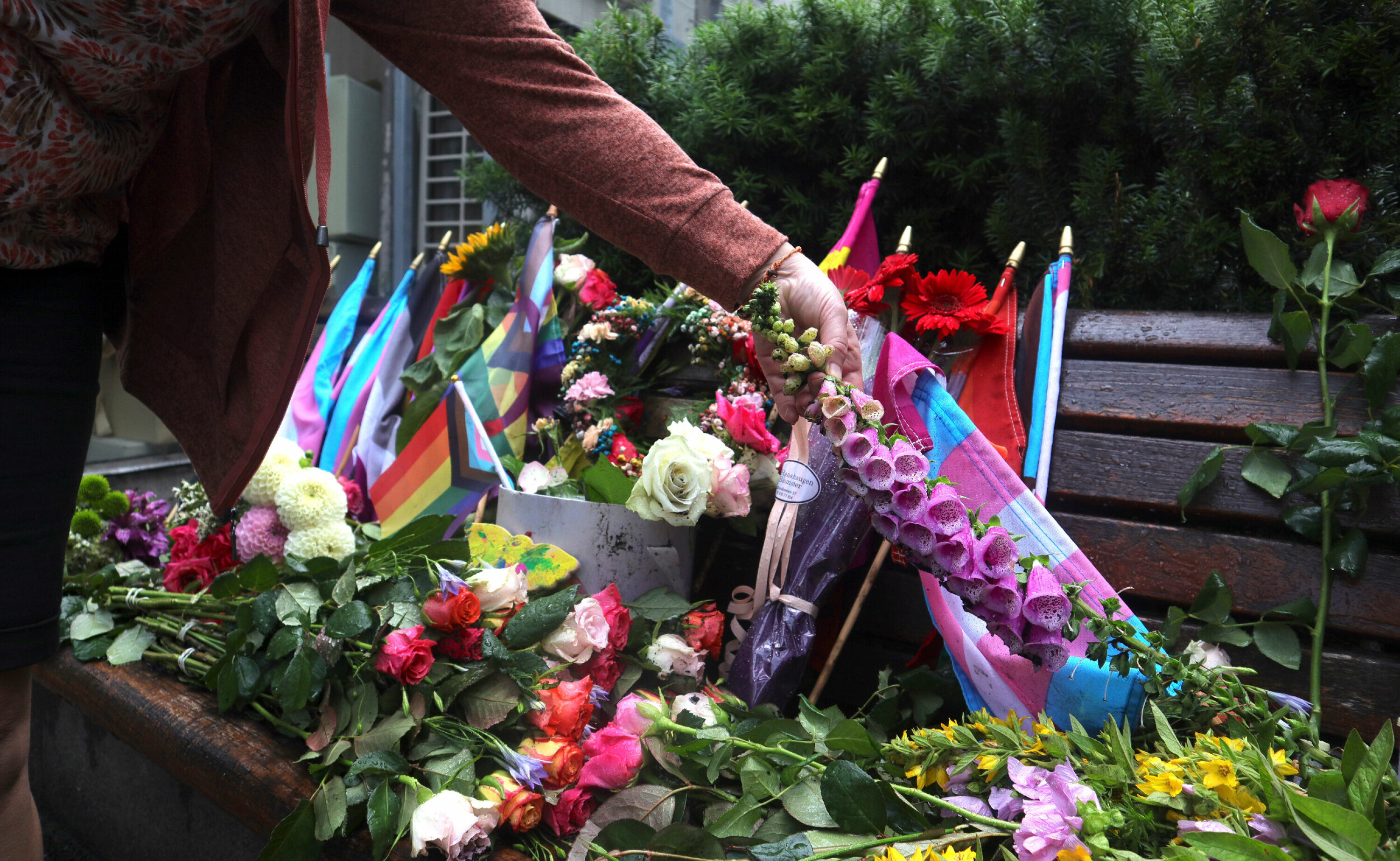 En kvinne legger ned blomster på Kim Frieles benk på Nationaltheatret i Oslo få dager etter terrorangrepet 25. juni.