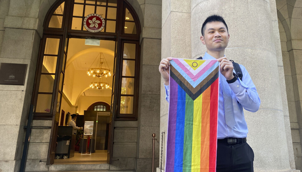 Nick Infinger poserer med et regnbueflagg etter å ha fått rettens medhold i at likekjønnede par skal ha tilgang på kommunale boliger i Hongkong.