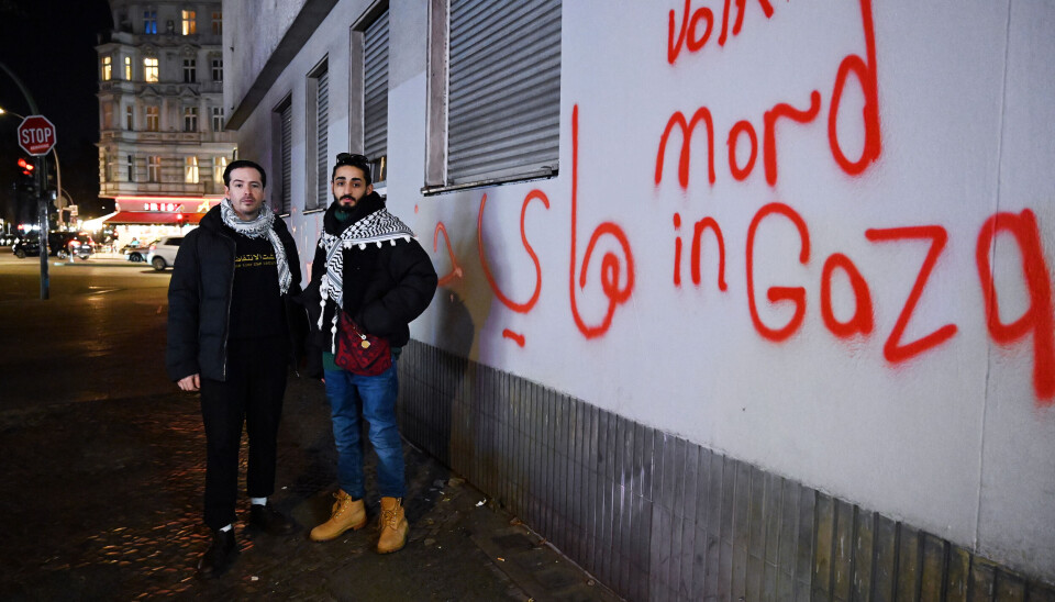 Udi og Mohammad, ved en vegg med påskriften «Folkemord i Gaza».
